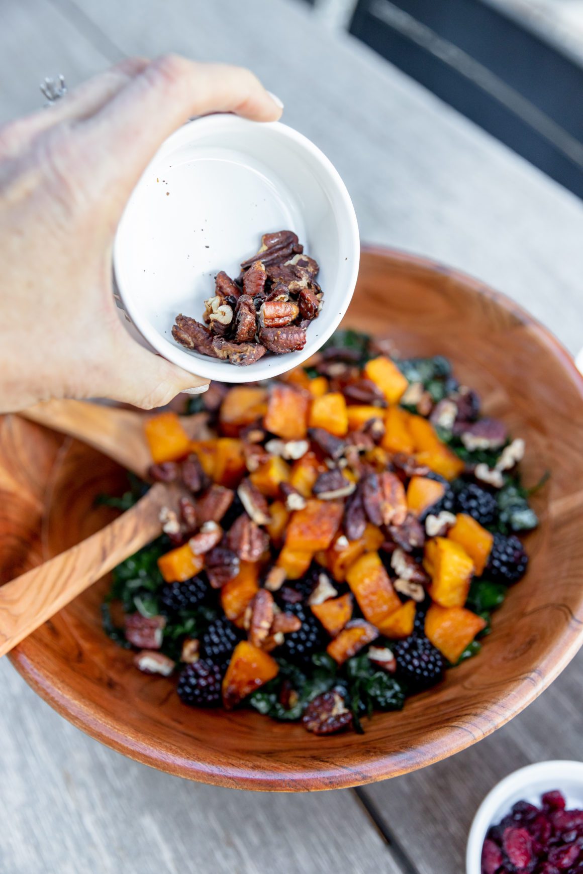 adding pecans to the butternut squash kale salad
